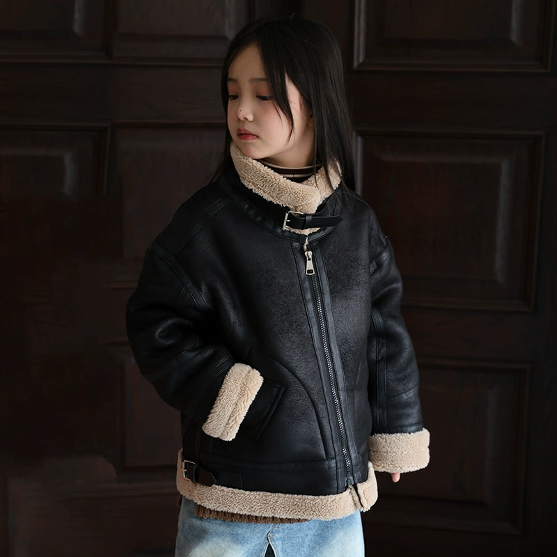 Child wearing a black leather jacket with beige trim against a dark background