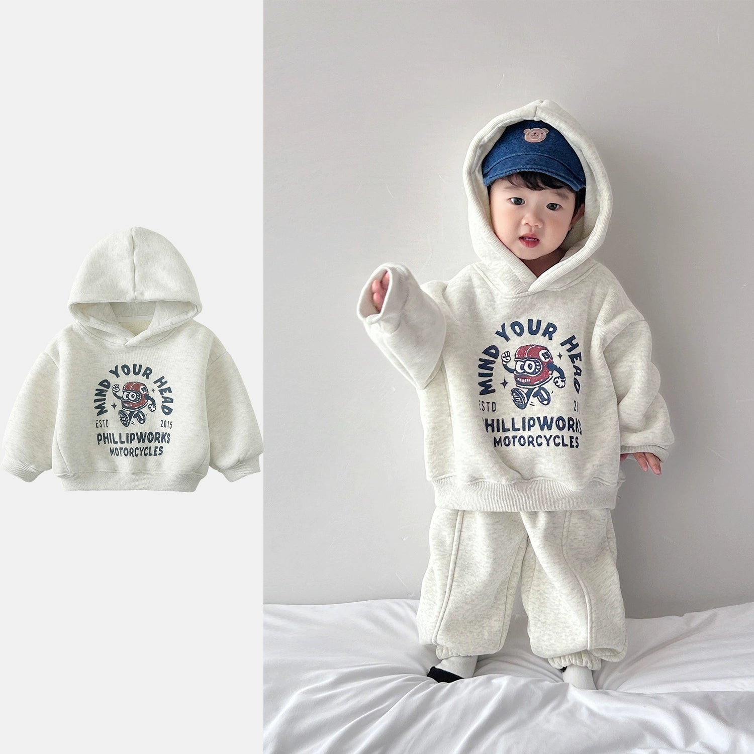 Child wearing a white hoodie with graphic design and text, standing on a bed.