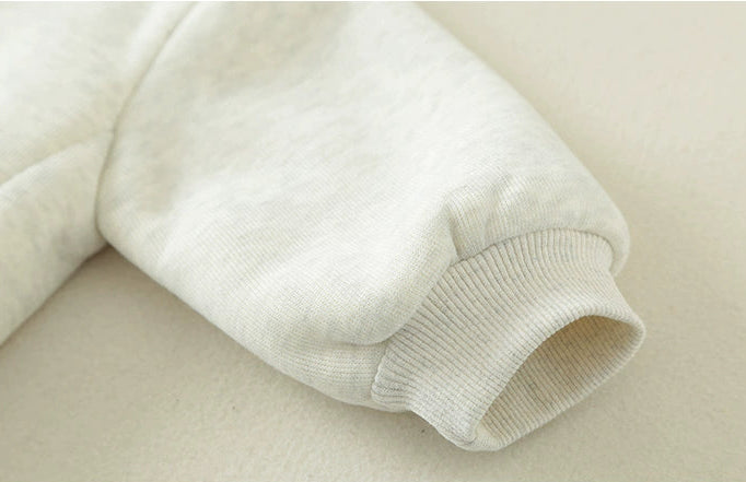 Close-up of a beige sweater sleeve on a beige background with text.