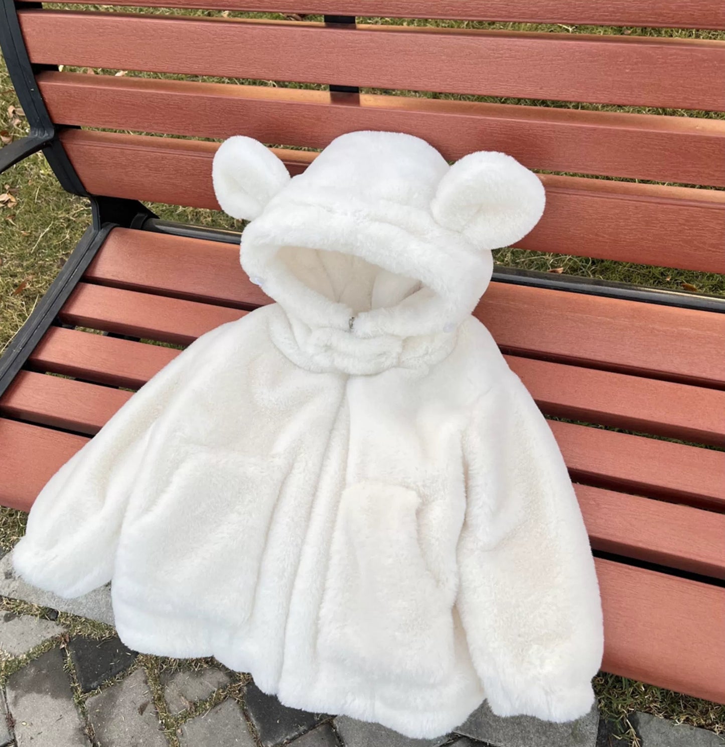 White fur coat with bear ears on a wooden bench