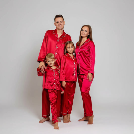 Family of four wearing matching red pajama sets in a decorated room.