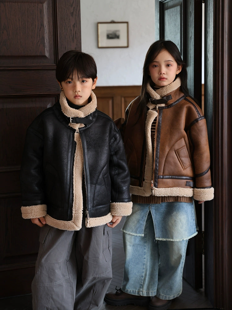 Two children wearing shearling jackets standing indoors.