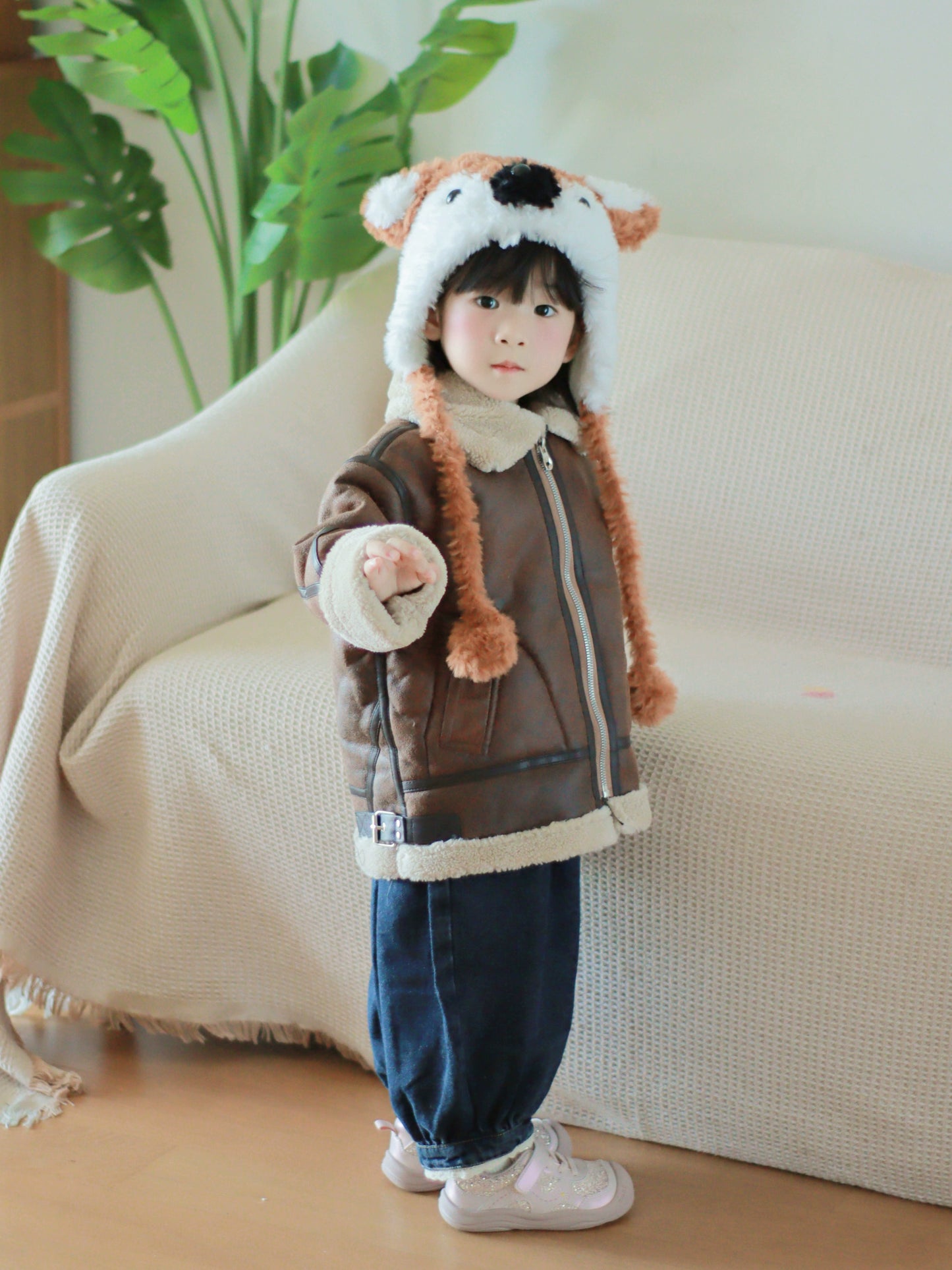 Child wearing a brown jacket with a fox hat in a living room setting