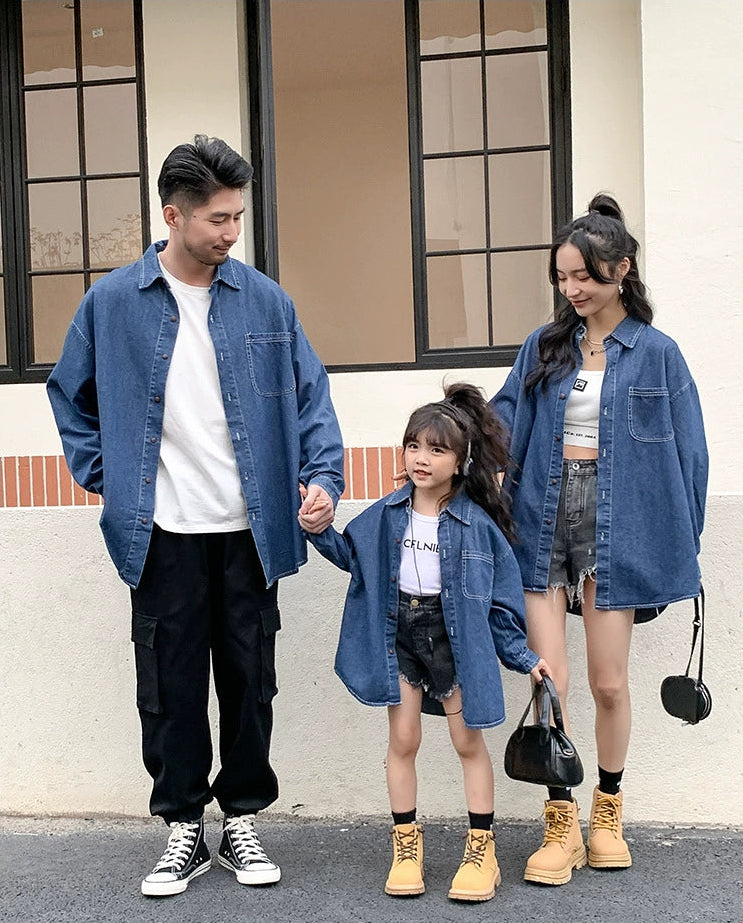 Family of three wearing matching denim outfits standing outdoors.