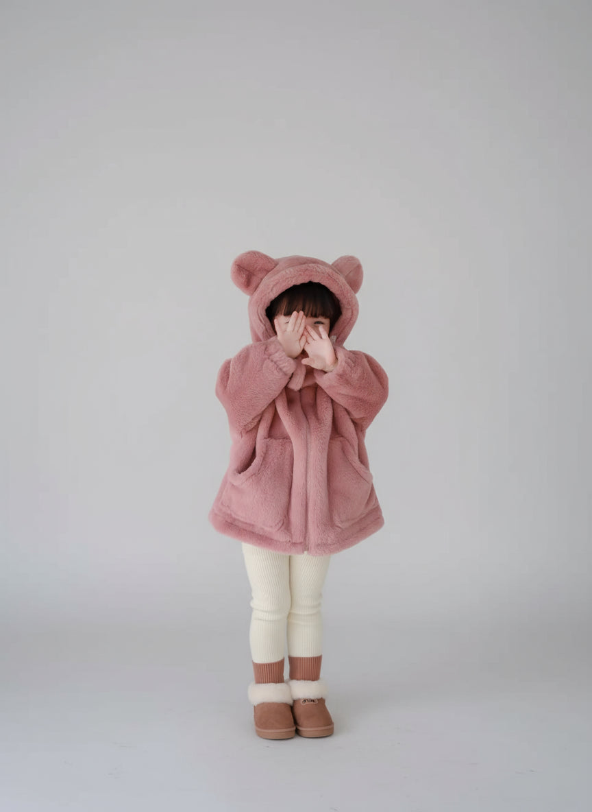 Child wearing a pink bear-themed hoodie on a light gray background