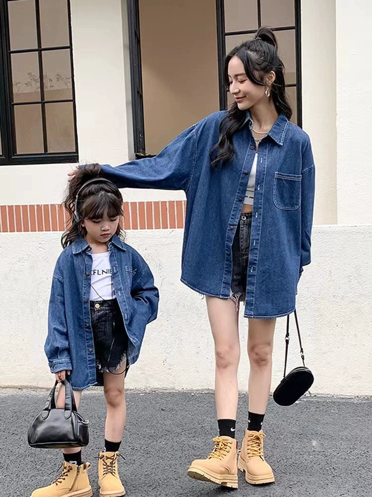 Two people wearing matching denim jackets outdoors.