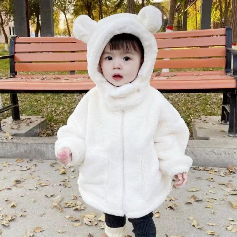 Child wearing a white bear-themed snowsuit in a park setting