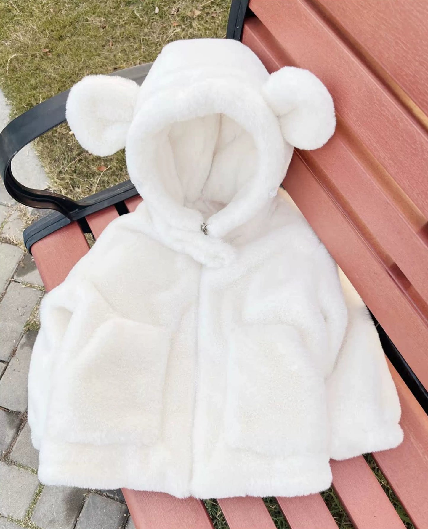 White hooded jacket with bear ears on a bench outdoors