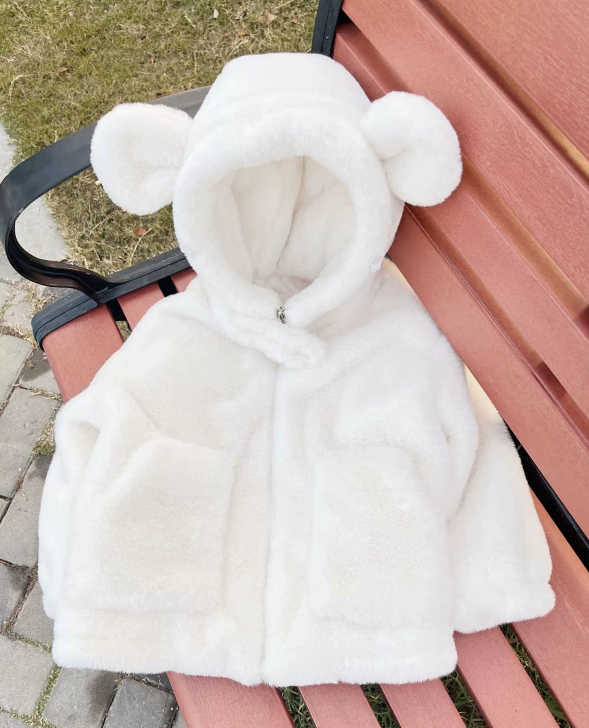 White hooded jacket with bear ears on a bench outdoors