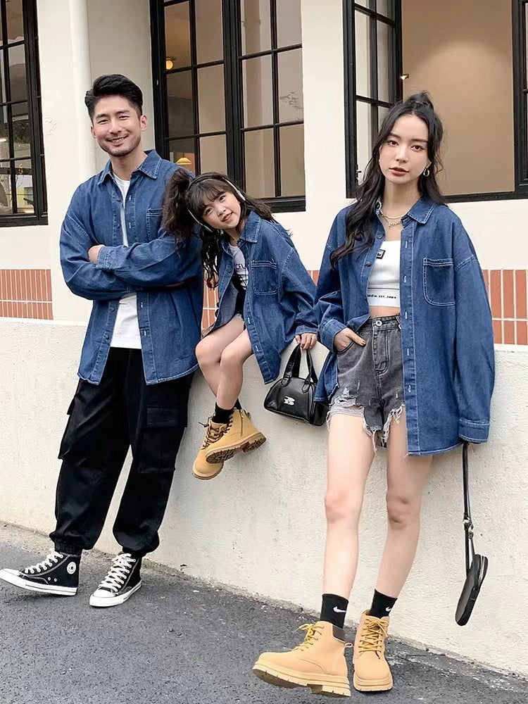 Three people wearing denim jackets standing against a building.