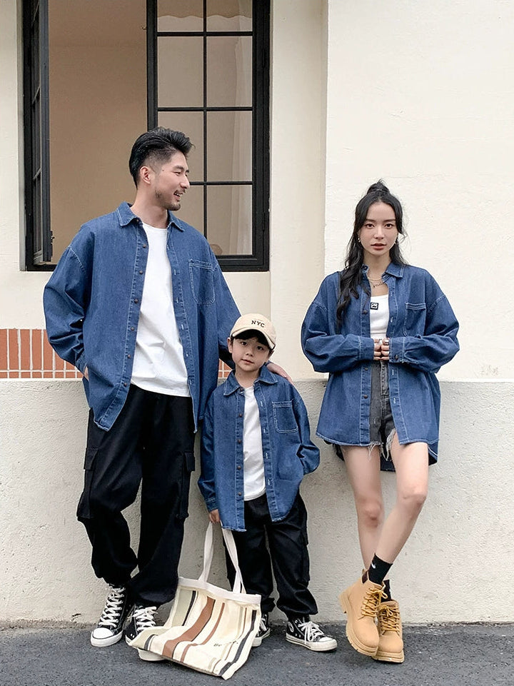 Family of three wearing denim outfits standing against a light-colored wall.