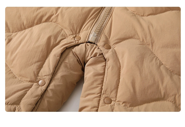 Close-up of a beige quilted jacket with buttons and zipper on a white background